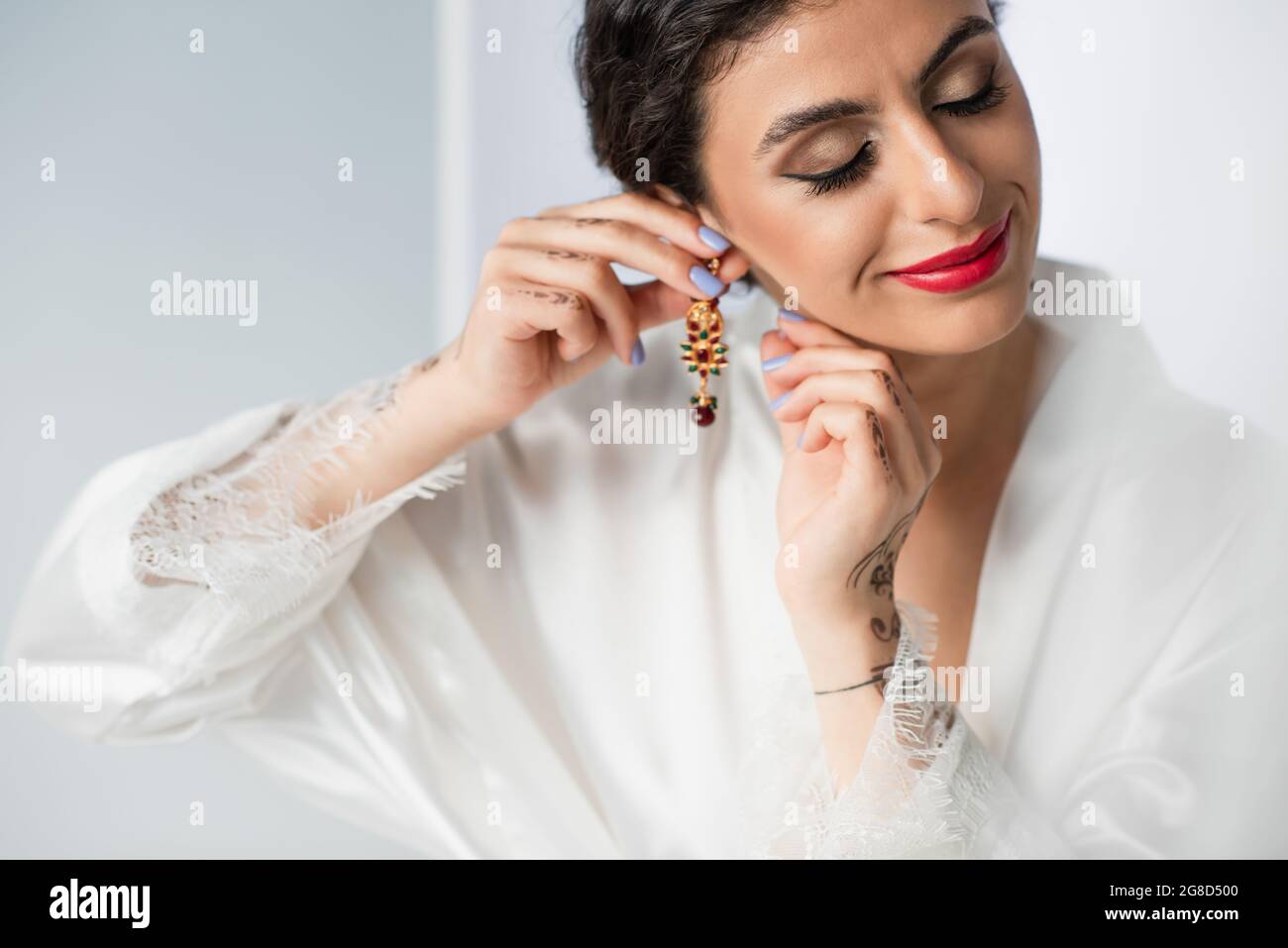 smiling indian bride wearing earring on white Stock Photo