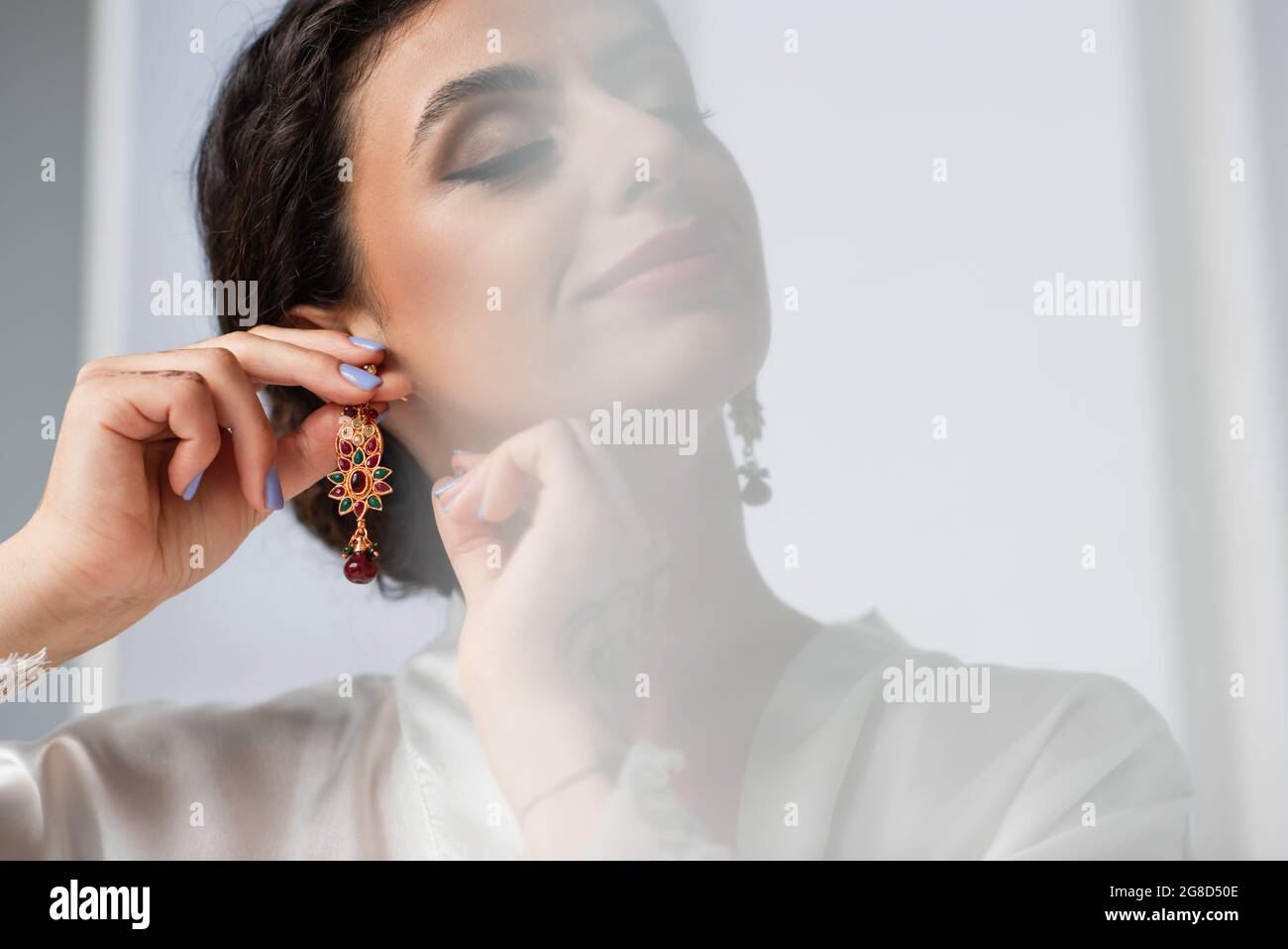young indian bride wearing earring on white Stock Photo