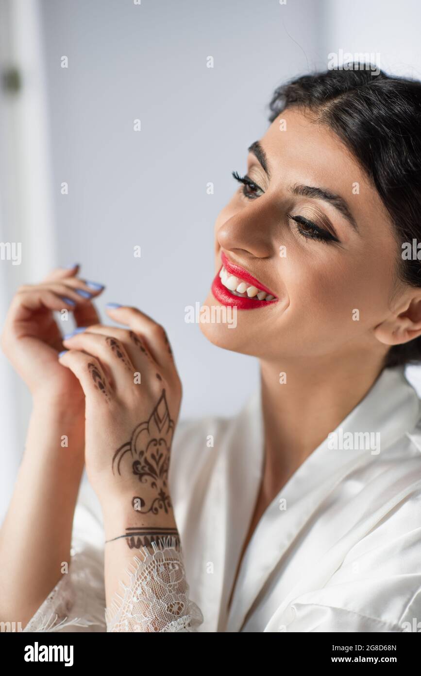 young and cheerful indian bride smiling on white Stock Photo