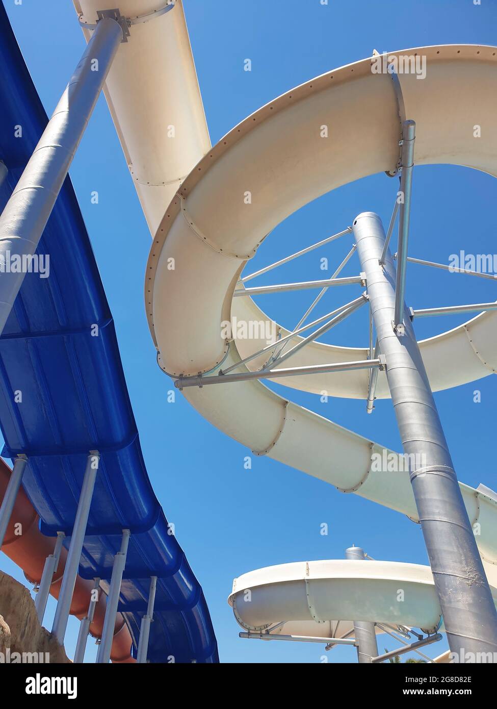 Screw water slide and speed slides from below at water park summer holiday.  Summertime background with copy space. Stock Photo