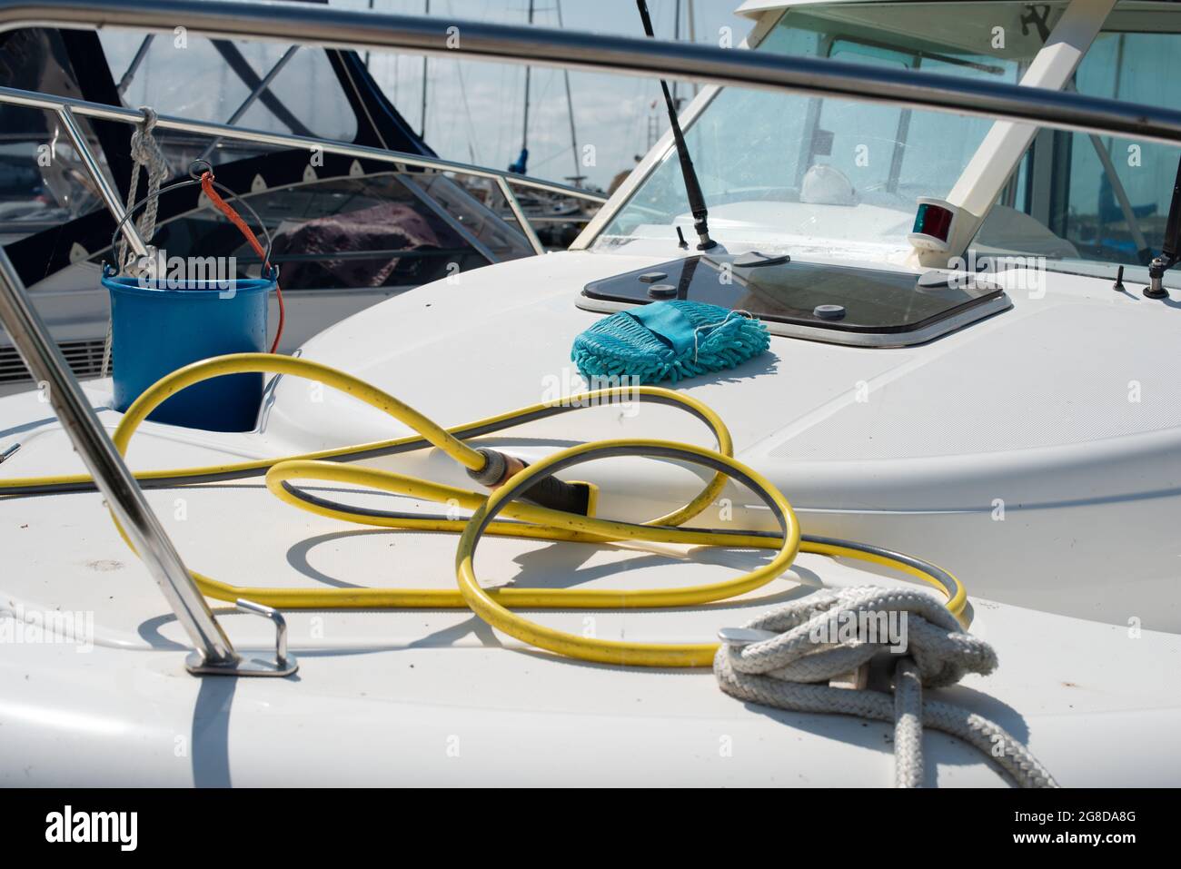 Boat cleaning equipment. Plastic bucket, hose with water spray gun, mop laying on the yacht