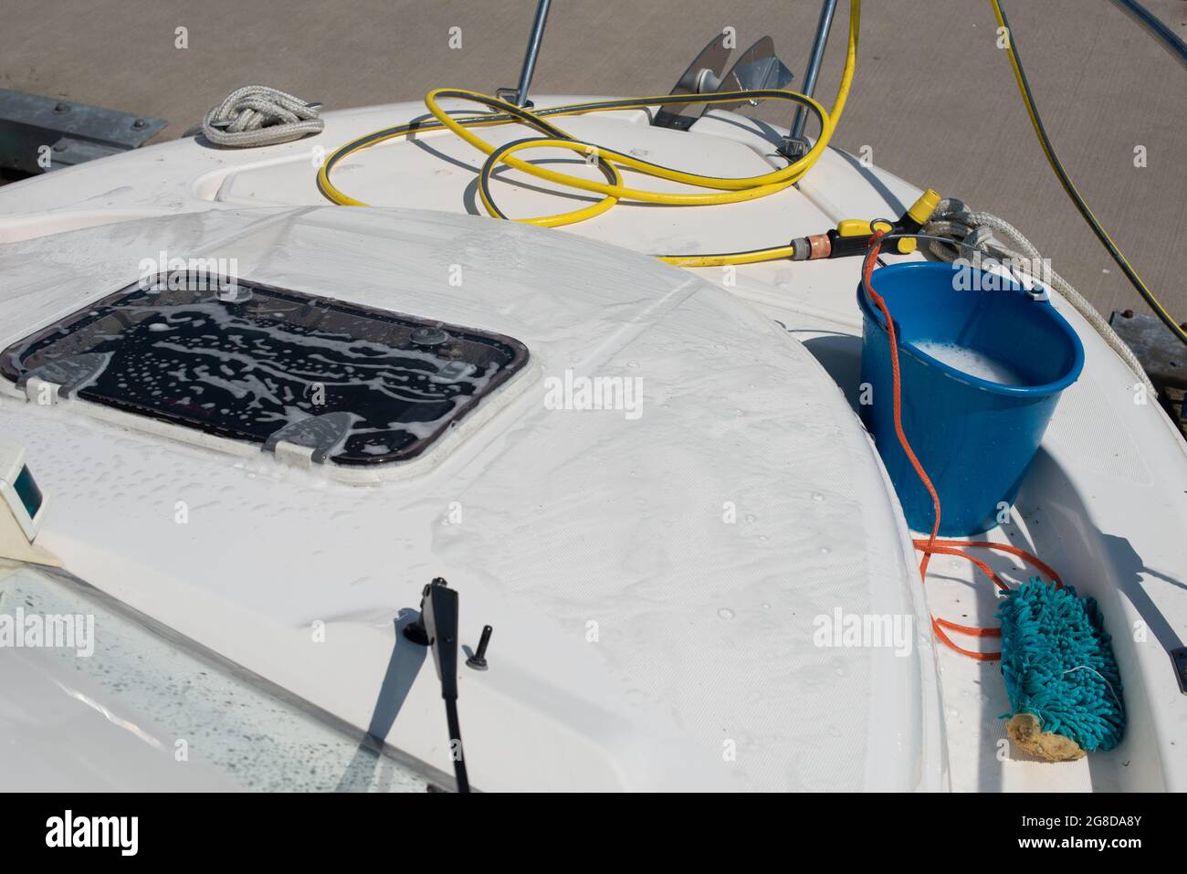 Boat cleaning equipment. Plastic bucket, hose with water spray gun, mop laying on the yacht