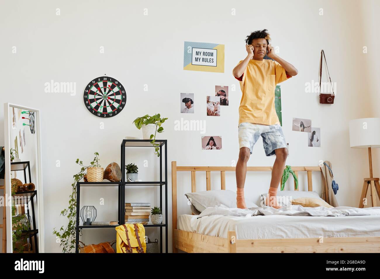 Wide angle portrait of mixedrace teenage boy jumping on bed while