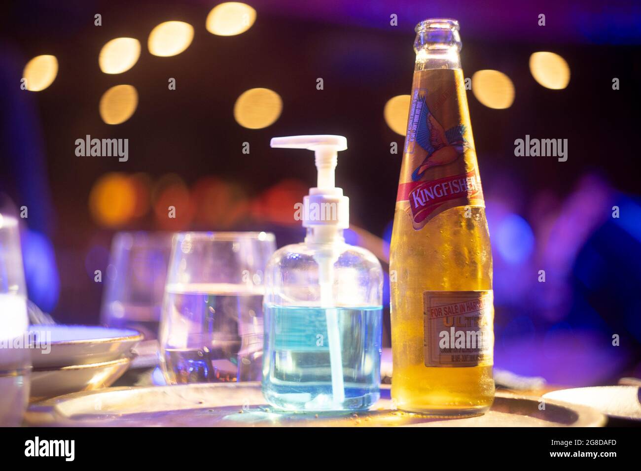 famous indian beer brand kingfisher bottle with bubble coming out with out of focus background lights with bokeh balls showing it placed in a bar club Stock Photo