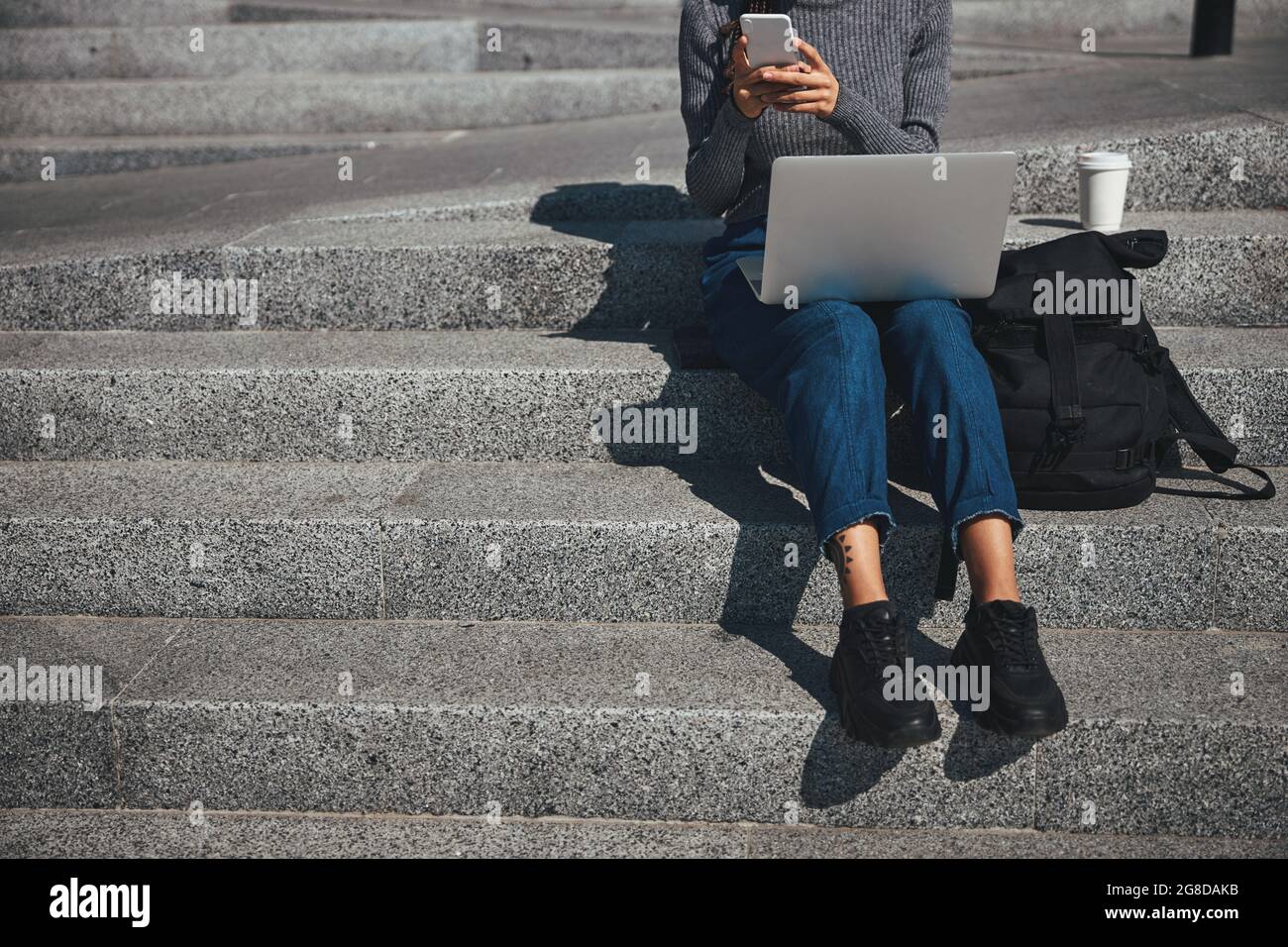 Woman with cornrows typing a text message on her cellular phone Stock Photo