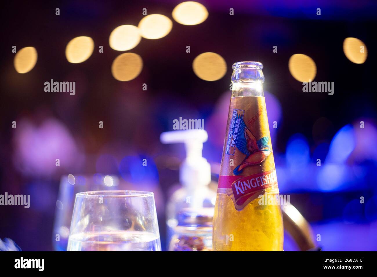 famous indian beer brand kingfisher bottle with bubble coming out with out of focus background lights with bokeh balls showing it placed in a bar club Stock Photo