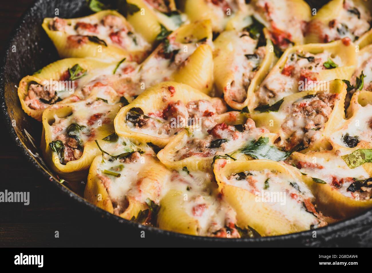 Skillet of baked jumbo shells pasta stuffed with ground beef, spinach