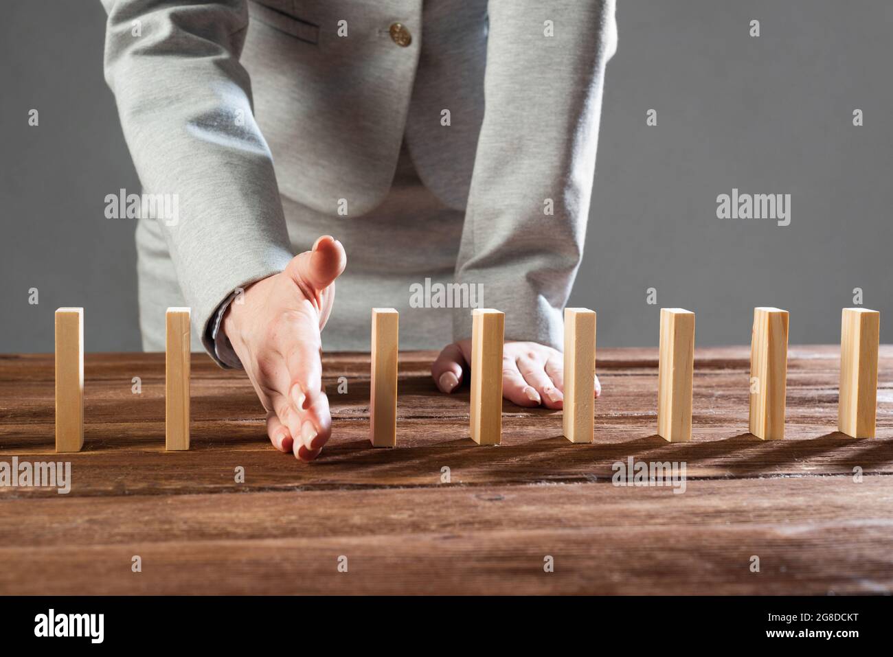 Business woman interrupting domino effect Stock Photo - Alamy