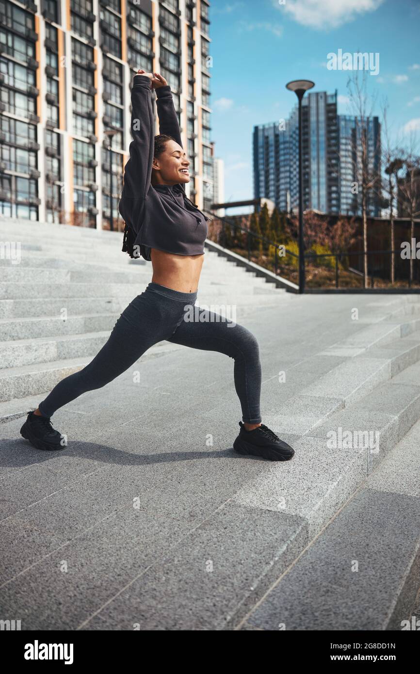 Smiling athletic female performing a stretching exercise outdoors Stock Photo