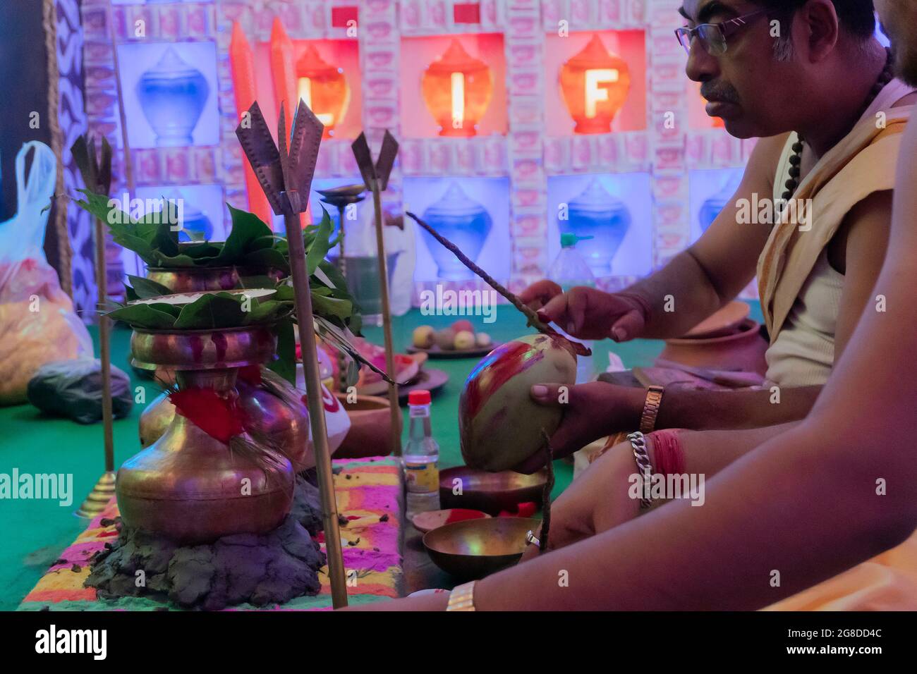 Howrah, West Bengal, India - 5th October 2019 : Hindu Bengali priests writing OM - Holy hindu words, on coconuts for worshipping Goddess Durga inside Stock Photo