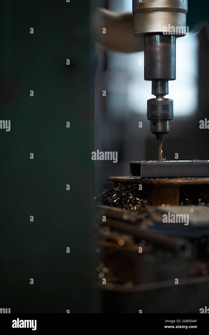 Close up of professional worker drilling holes in metal piece on lathe