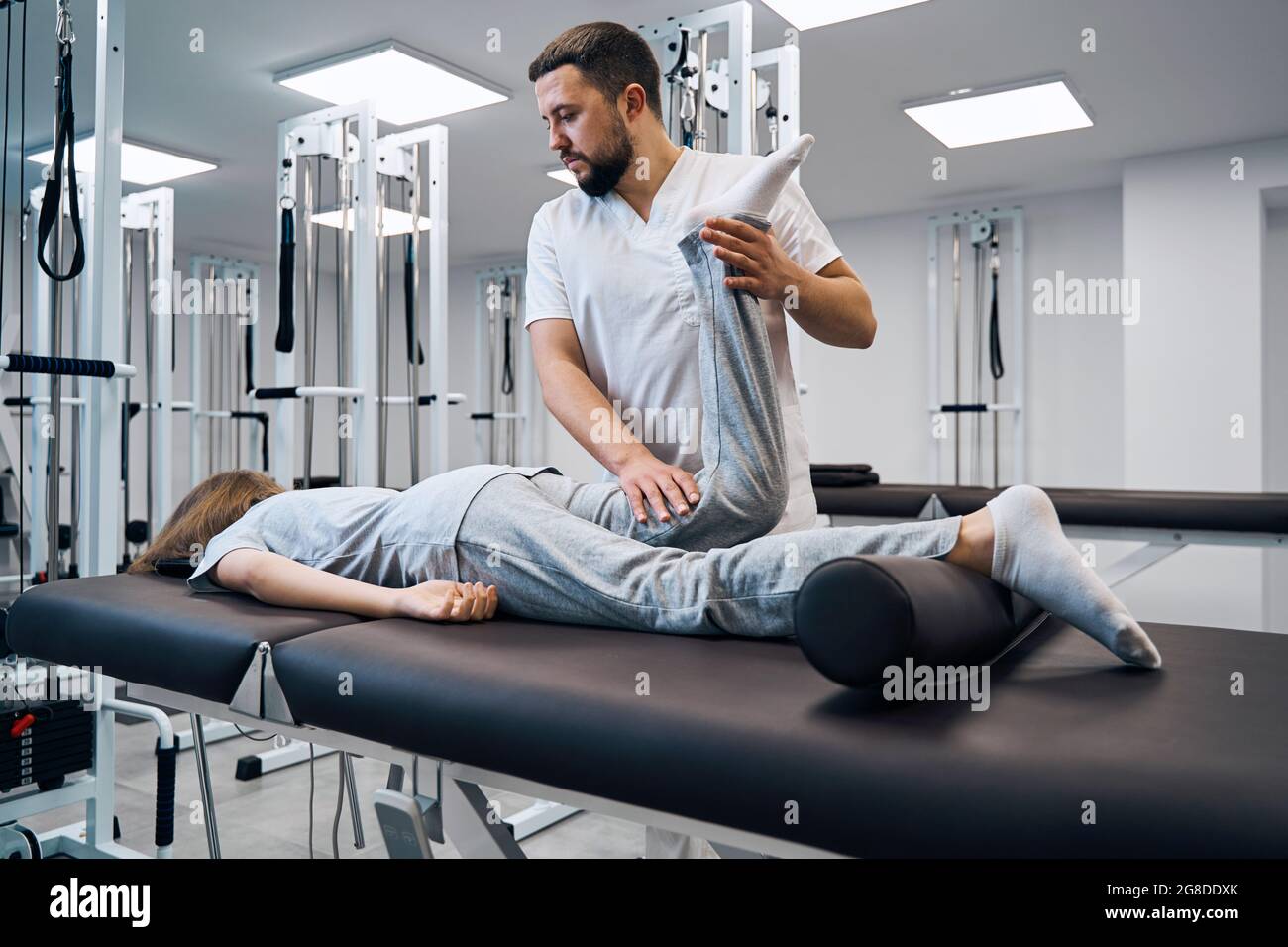 Physiotherapist controlling knee of patient in bright rehab clinic closeup. Massage therapist Stock Photo