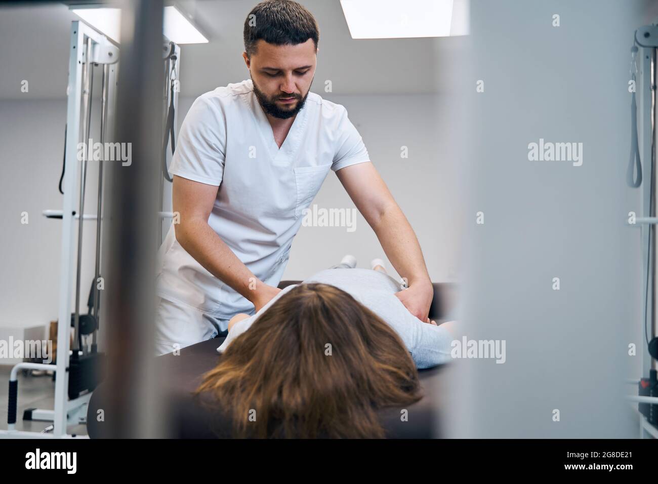 Physical therapist examines girl with spinal deformity on procedure at rehabilitation center Stock Photo