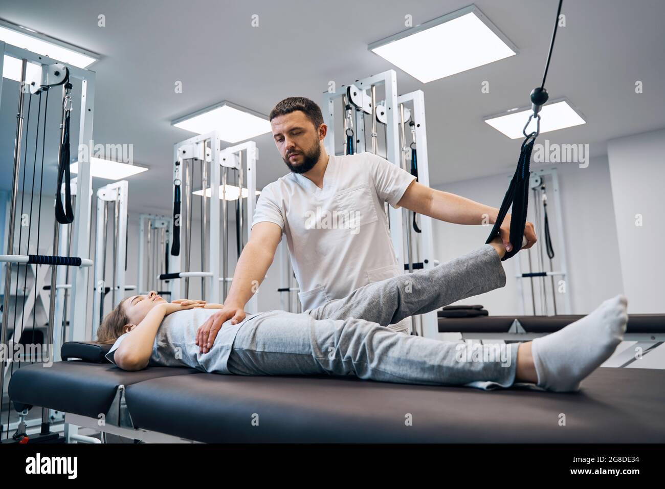 Girl lying on physical therapy bed, doing exersises on elastic strength