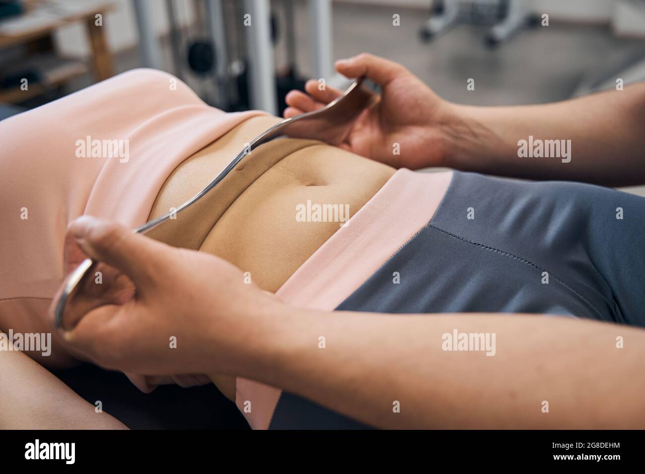 Chiropractor massages woman using IASTM tool for scraping muscles in rehab clinic gym closeup Stock Photo
