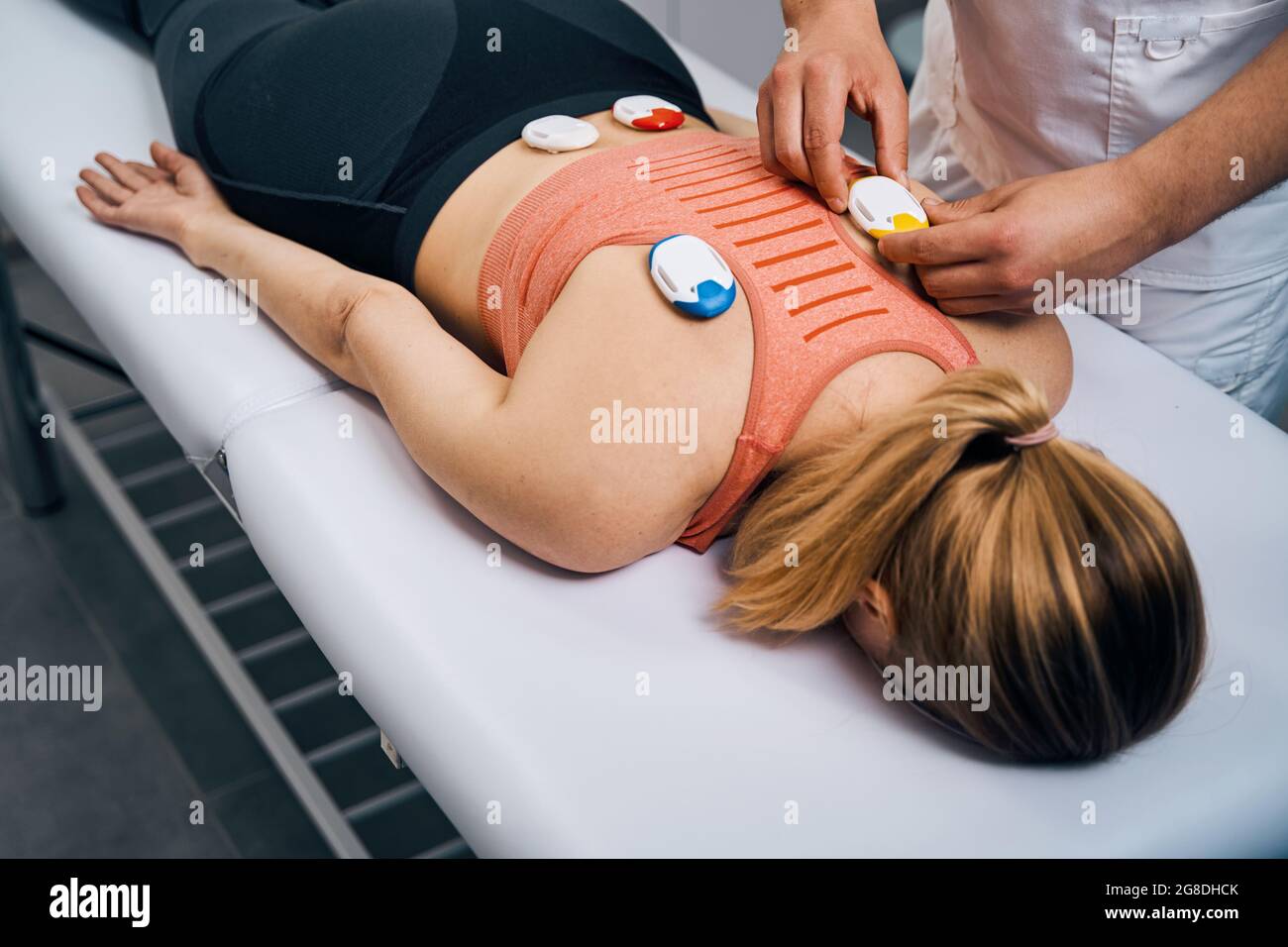 Myostimulation. Correction of scoliosis in woman with electrostimulators. Female patient on massage Stock Photo