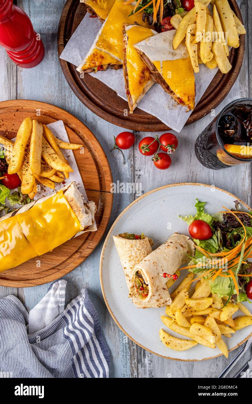 cheddar cheese burrito, wrap and quesadilla with french fries and salad. Stock Photo