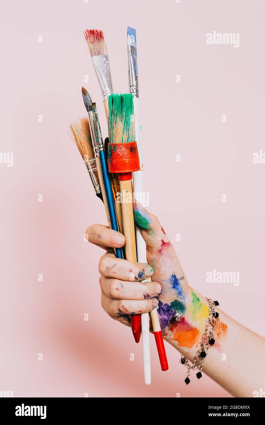 Creative background. Female artist hand holding colorful paintbrushes.  Paints and brushes background. Art class, art school. Pink artistic  background Stock Photo - Alamy