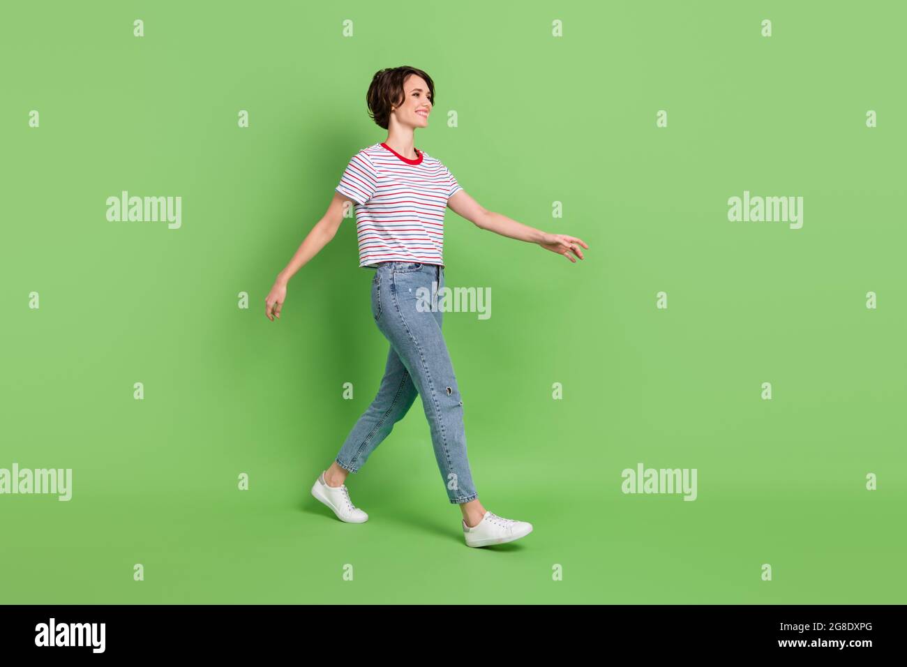 Full length body size profile side view of pretty cheerful girl walking isolated over green pastel color background Stock Photo