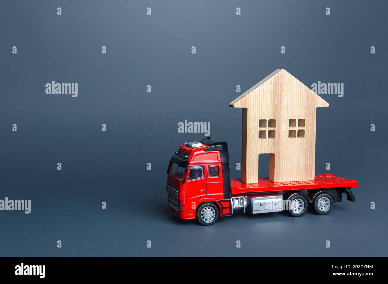Red truck transports the residence house. Delivery services to another house. A moving company. Transportation of real estate. Resettlement program fo Stock Photo