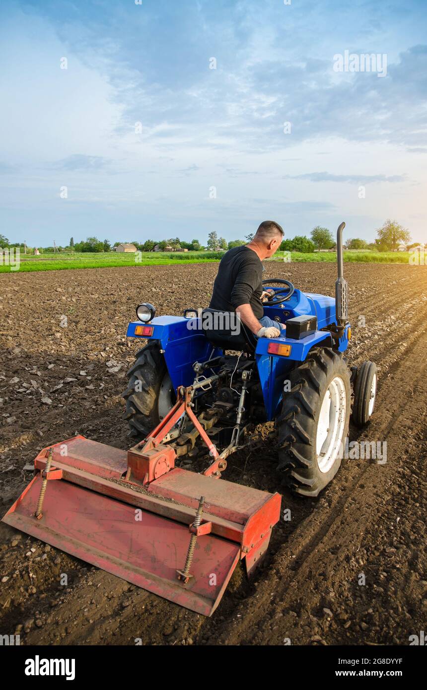 A farmer is cultivating a field before replanting seedlings. Milling soil. Softening the soil and improving its qualities. Farming. Preparatory earthw Stock Photo