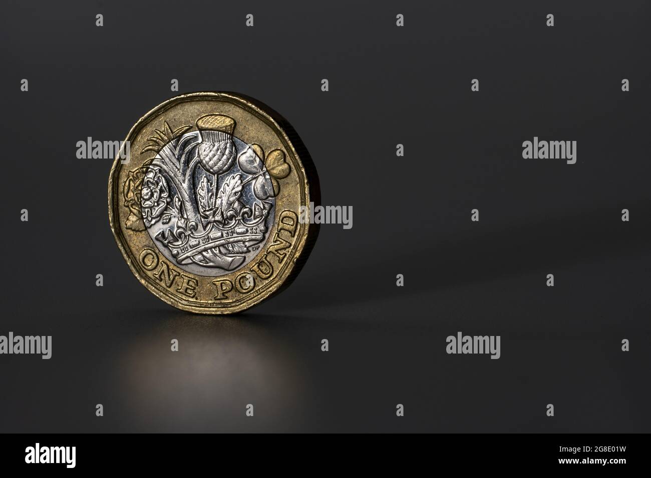 British one pound coin macro photo. Coin withn the signs of circulation, worn state. Isolated on the grey background. Stock Photo