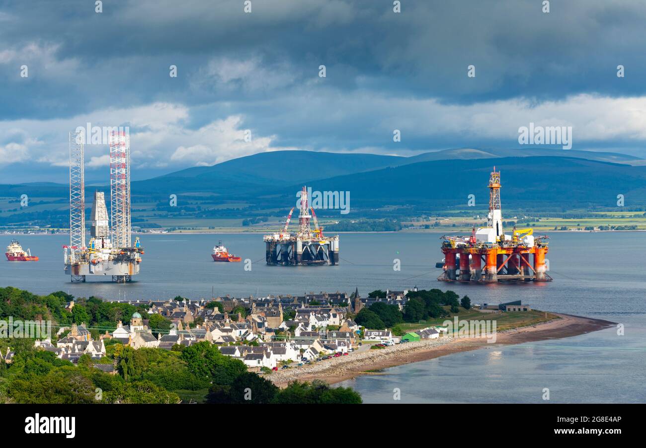 View of Cromarty village and old and gas industry platforms and rigs moored in Nigg Bay on Black Isle on Cromarty Firth, Ross and Cromarty, Scotland, Stock Photo