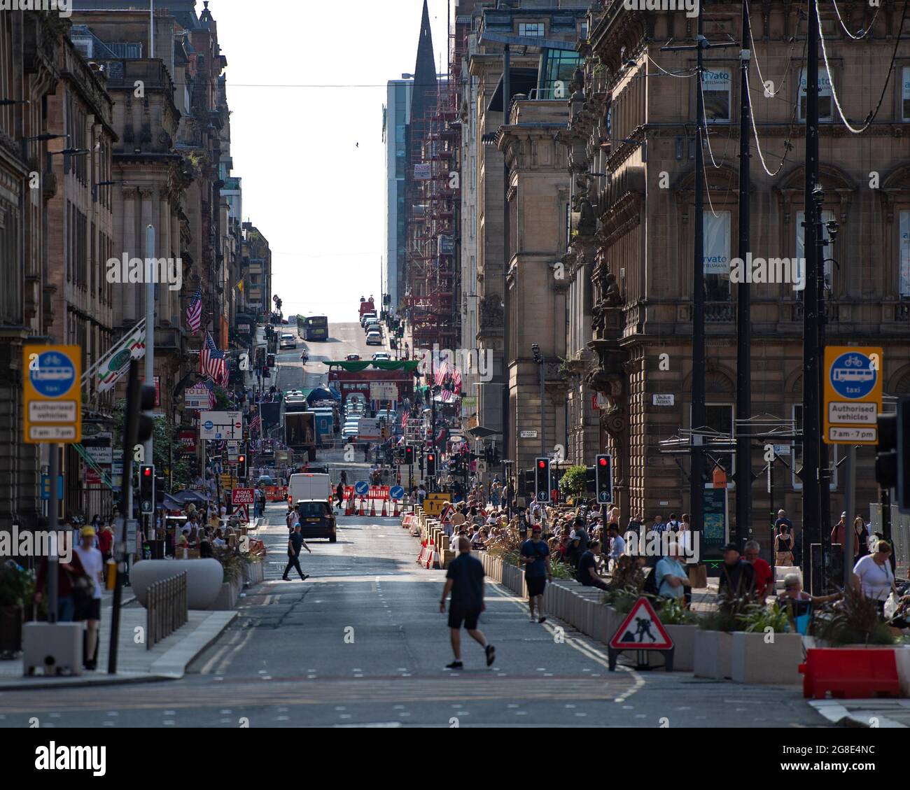 Glasgow, Scotland, UK. 19th July, 2021. PICTURED: On the film set of the new Hollywood blockbuster movie of Indiana Jones 5, people walk around and look at the sights in the city centre. They take pictures and selfies with their cameras phones. The streets are decorated with stars and strips flags and bunting and the Harrison Ford double was seen riding horse back through the streets of Glasgow. Credit: Colin Fisher/Alamy Live News Stock Photo