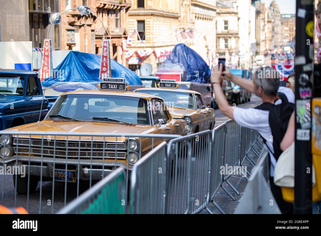 Glasgow, Scotland, UK. 19th July, 2021. PICTURED: On the film set of the new Hollywood blockbuster movie of Indiana Jones 5, people walk around and look at the sights in the city centre. They take pictures and selfies with their cameras phones. The streets are decorated with stars and strips flags and bunting and the Harrison Ford double was seen riding horse back through the streets of Glasgow. Credit: Colin Fisher/Alamy Live News Stock Photo