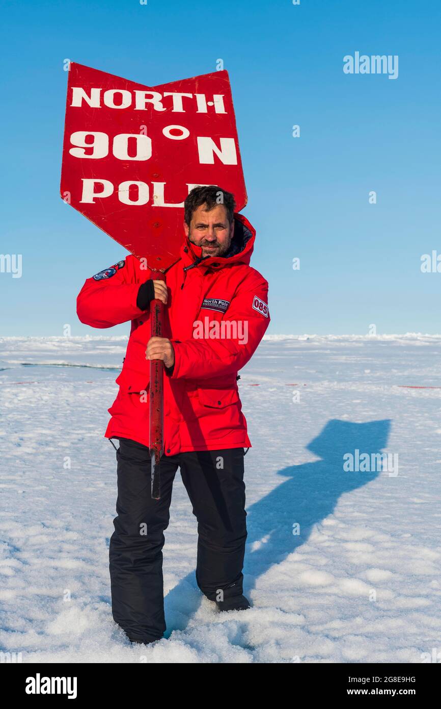 Man posing with a North Pole sign on the North Pole, Arctic Stock Photo