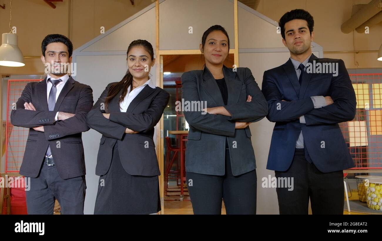 Closeup of four Indian business people standing in a line with their arms crossed, smiling Stock Photo