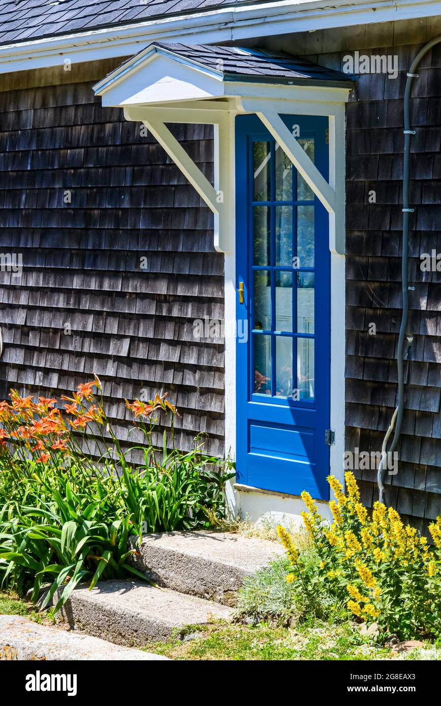 A charming blue door and gabled overhang on a shingle-side house welcomes walkers along the main road on Mohegan Island, Maine. Copy space. Stock Photo