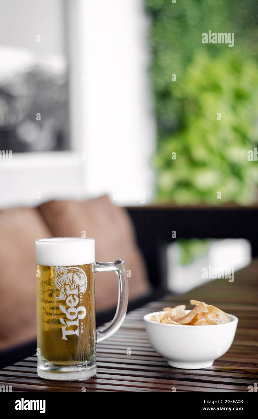 glass of draft Tiger Beer and Taro chips on outdoor bar terrace table in singapore Stock Photo