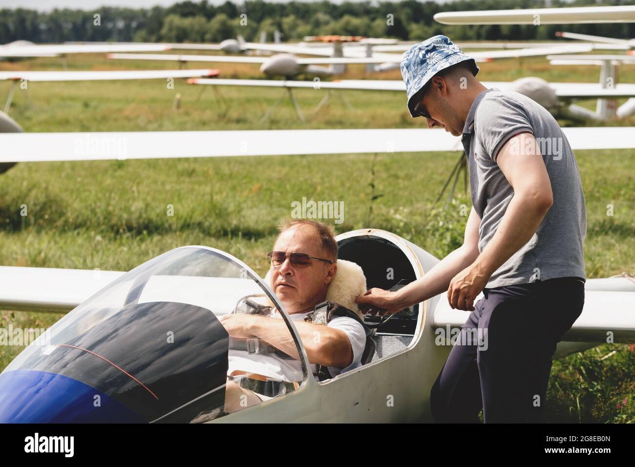 Soaring club, getting ready for the flight on glider airplane. Small aviation sport. Two man checking cabin instrument panel of vintage airplane Stock Photo