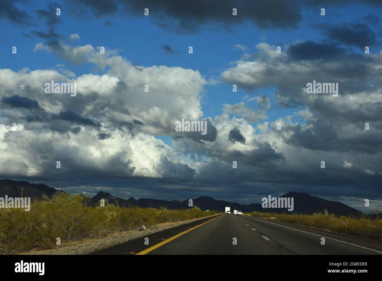 View from inside the car while driving on the highway towards the mountain with rain clouds in the sky. Cumulostratus cloud. Nimbostratus cloud. Stock Photo