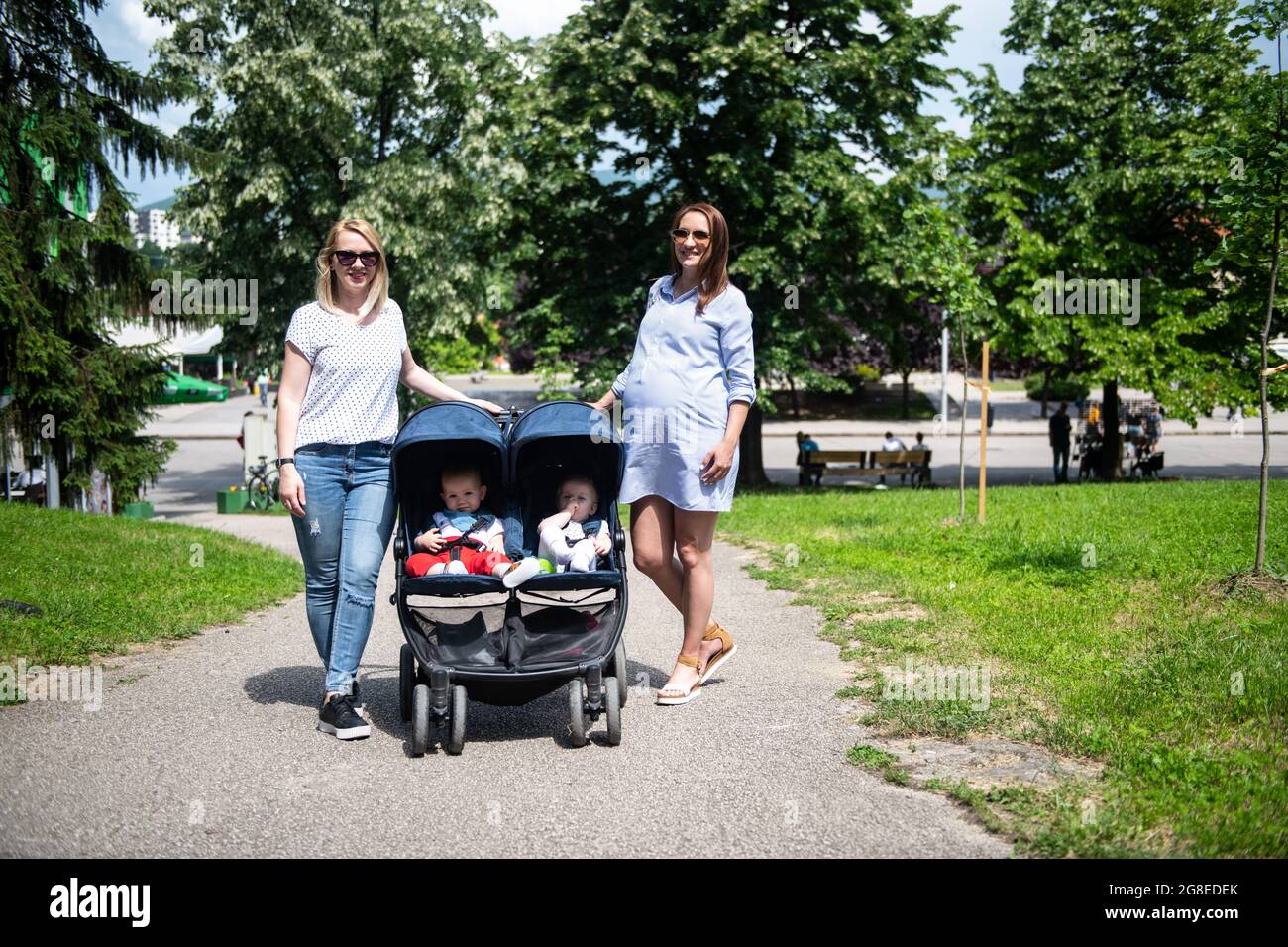 Young Mother With Friend Walking With Her Babies and Carries It in a  Beautiful Pushchair Stock Photo - Alamy