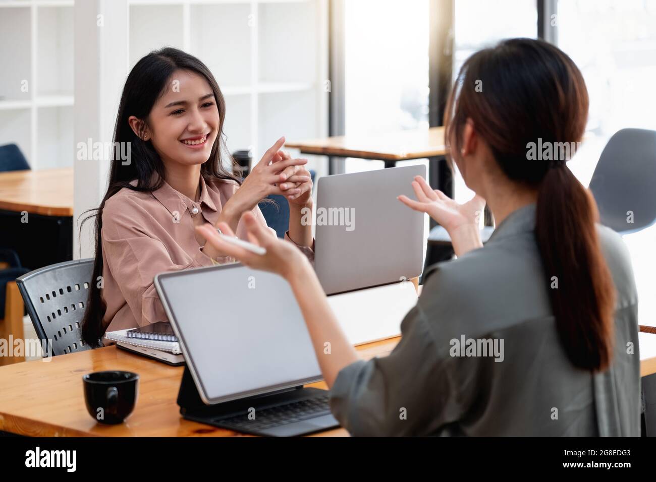 Coworkers team at work. Group of young asian business people in trendy casual wear working together in creative office with laptop computer Stock Photo