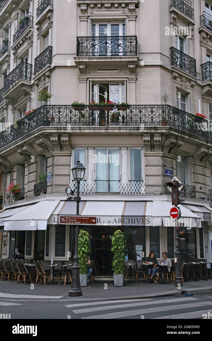 Paris, France :  Elegant apartment building in the Marais district, with a cafe on the ground floor with outdoor tables by the sidewalk. Stock Photo