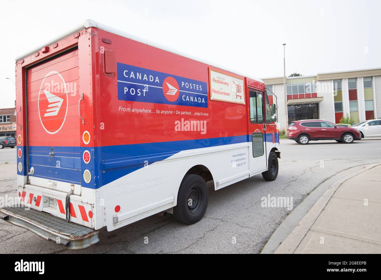 A Canada Post delivery truck is driving and approaches  the road for mail delivery service. Stock Photo