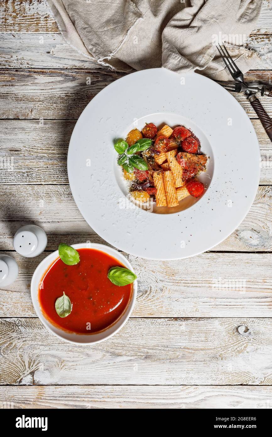 Penne pasta with tomatoes, spices, Parmesan cheese and fresh basil. Tomato sauce. Traditional dish of classic Italian cuisine in a white plate on a wo Stock Photo