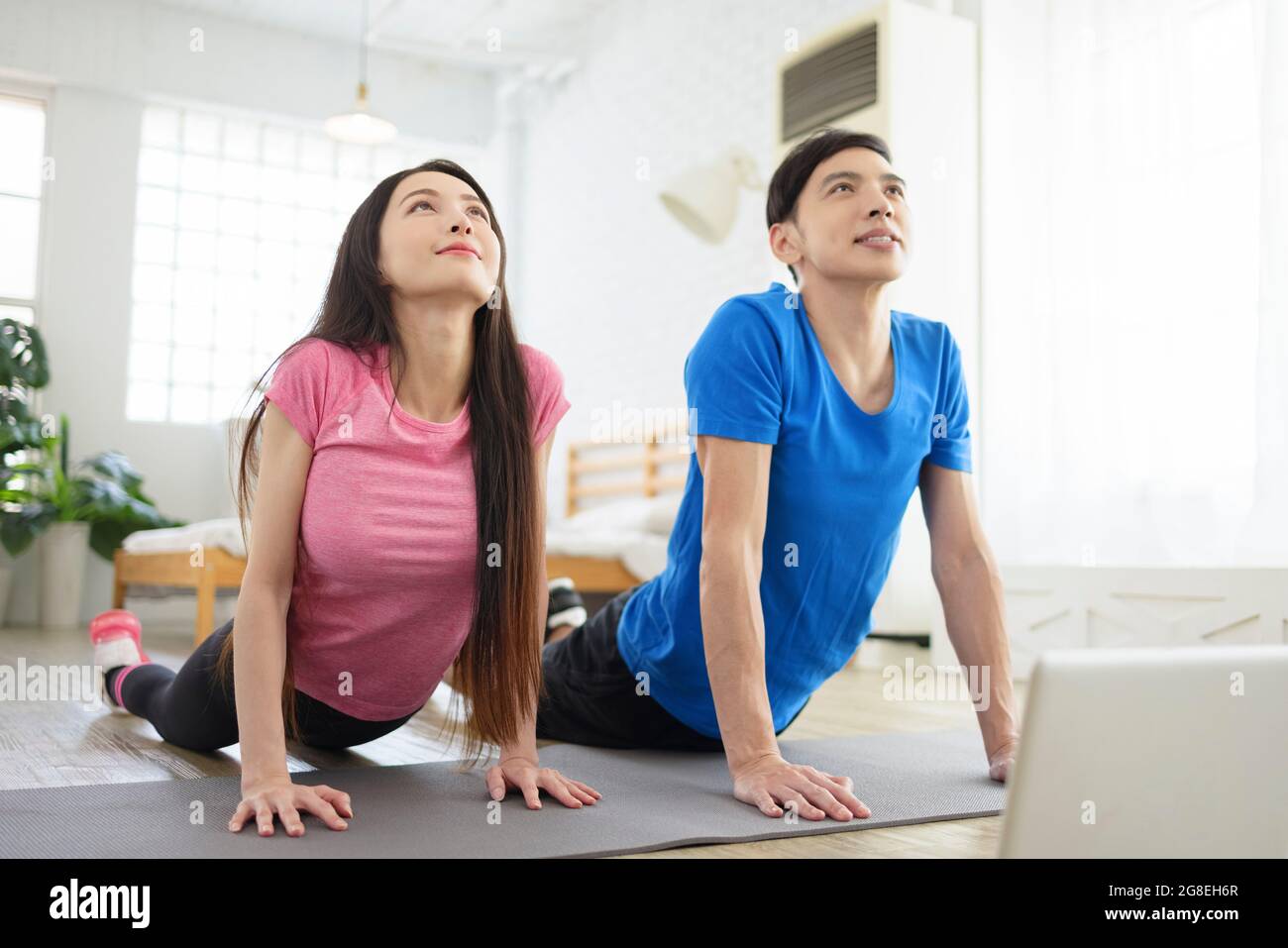 Young couple exercising at home,  watching videos on laptop. Stock Photo