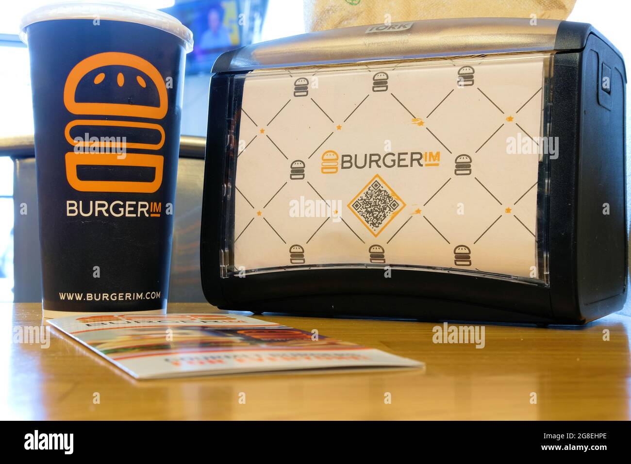 Drink cup, napking dispenser, and brochure at a Burgerim restaurant; an Israeli fast food hamburger franchise featuring fast-casual gourmet burgers. Stock Photo