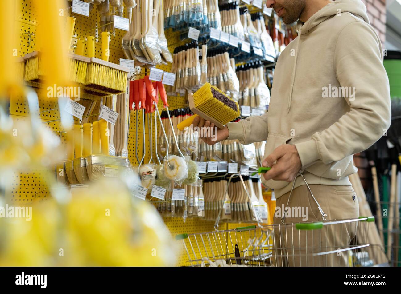 Man in hoodie choosing brush in household department or hardware store Stock Photo