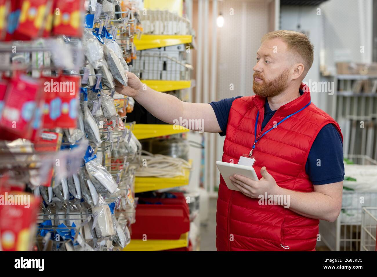 Bearded man with digital tablet checking goods on large display Stock Photo