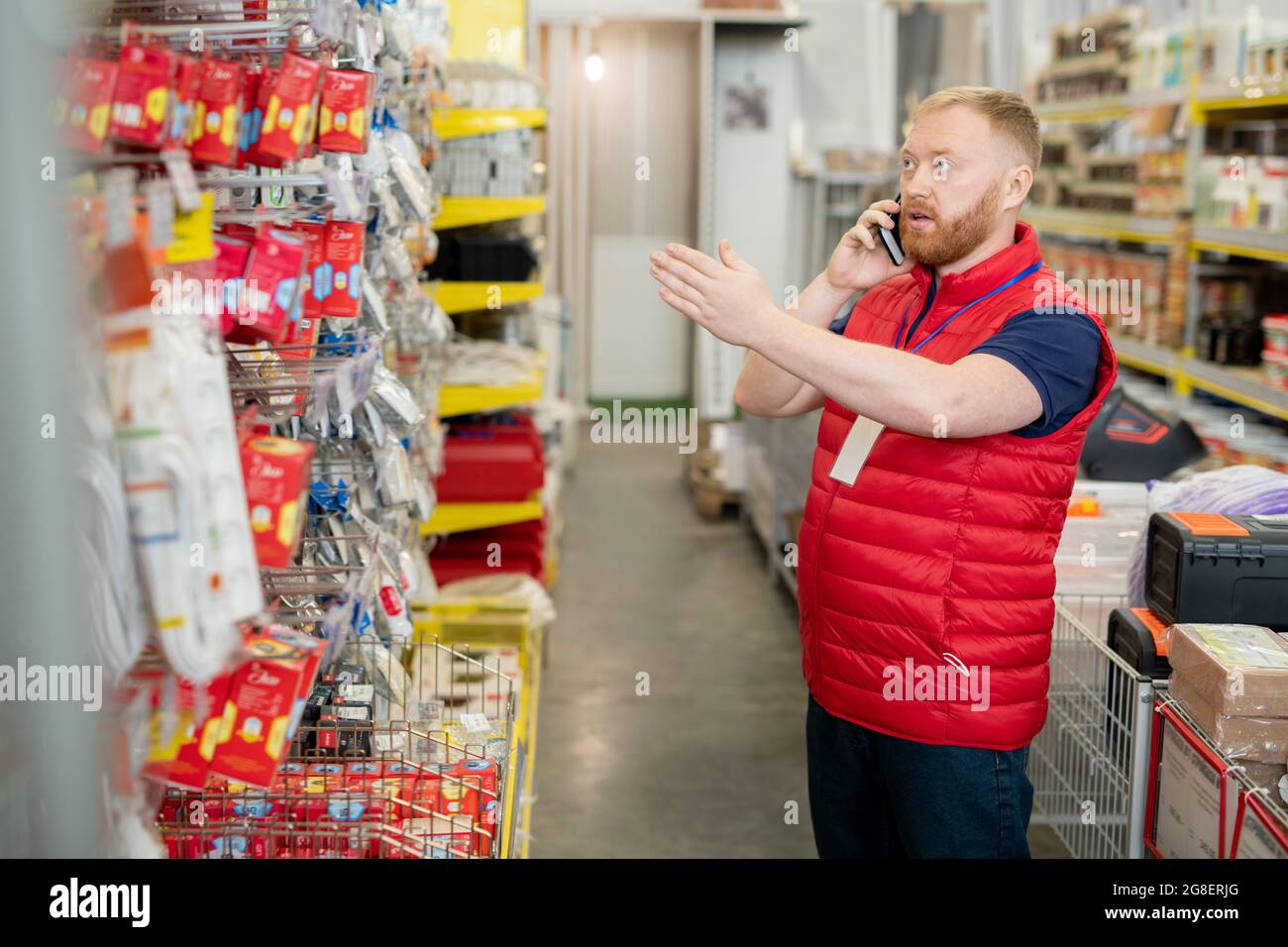 Confident manager talking to client on smartphone in hardware store Stock Photo
