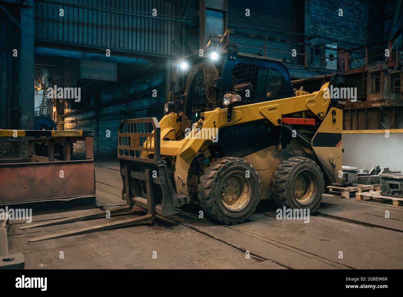 Small loading tractor or mower at work in metallurgical factory workshop. Stock Photo