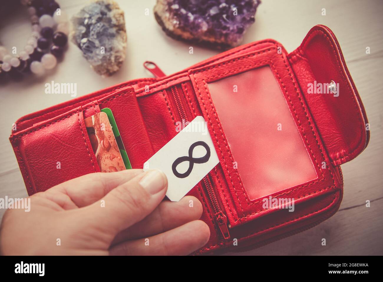 manifesting money concept close up view of woman person hand holding red wallet and symbol of infinity to attract more wealth and money 2G8EWKA