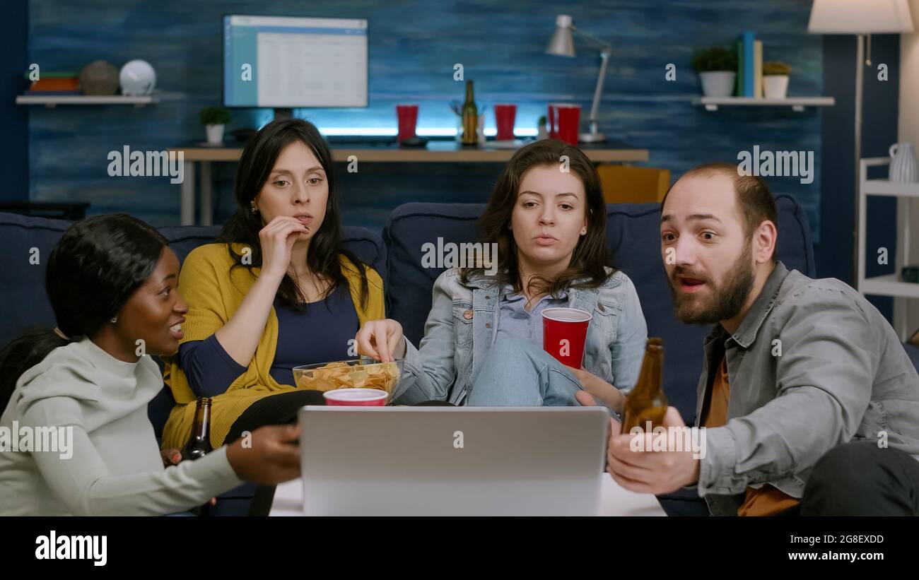 Multiracial friends relaxing on couch while watching comedy film
