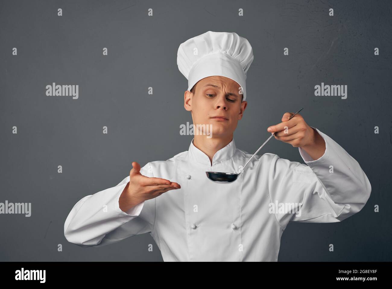 a cook with a ladle in his hands is trying a restaurant dish ...