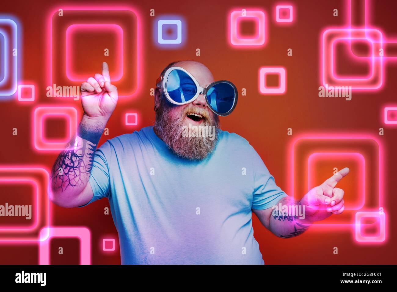 Fat happy man with beard, tattoos and sunglasses dances music Stock Photo
